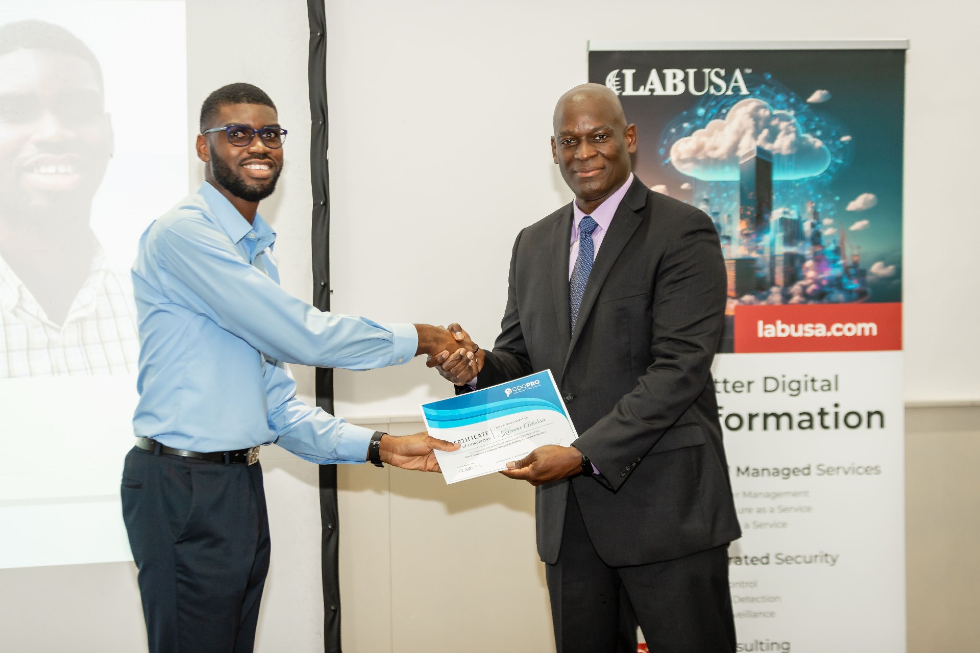 A man shaking hands with another man while handing him a certificate