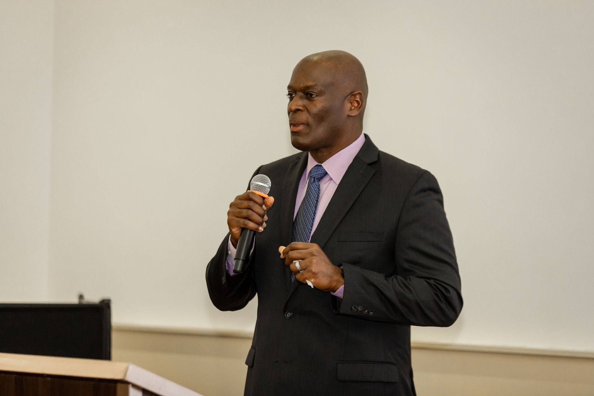 A man in a suit holding a microphone speaking