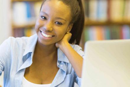 Young African-American female smiling in front of a laptop