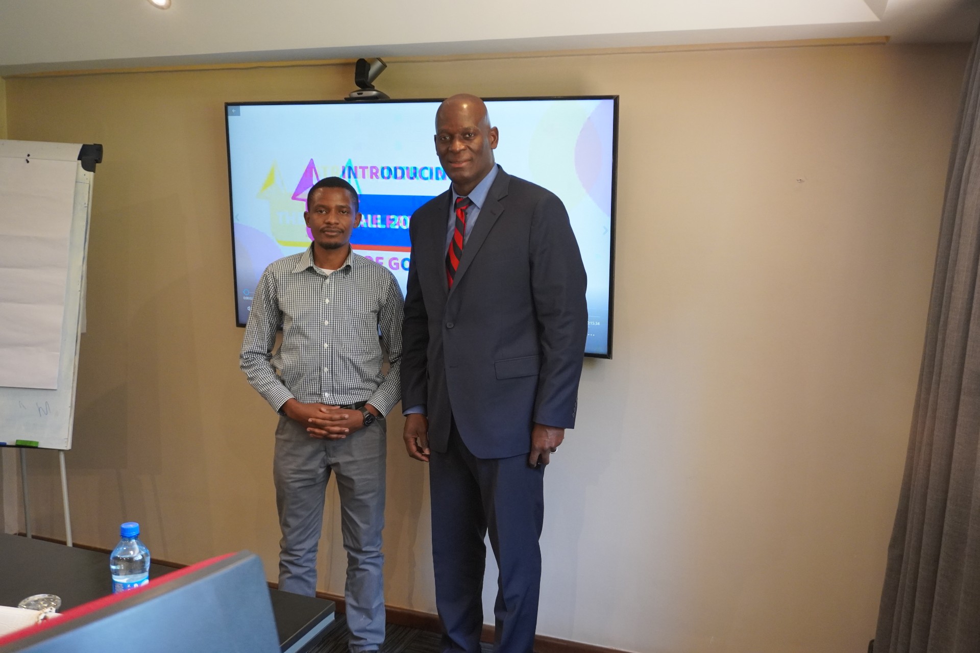 Two men standing side by side in front of a television