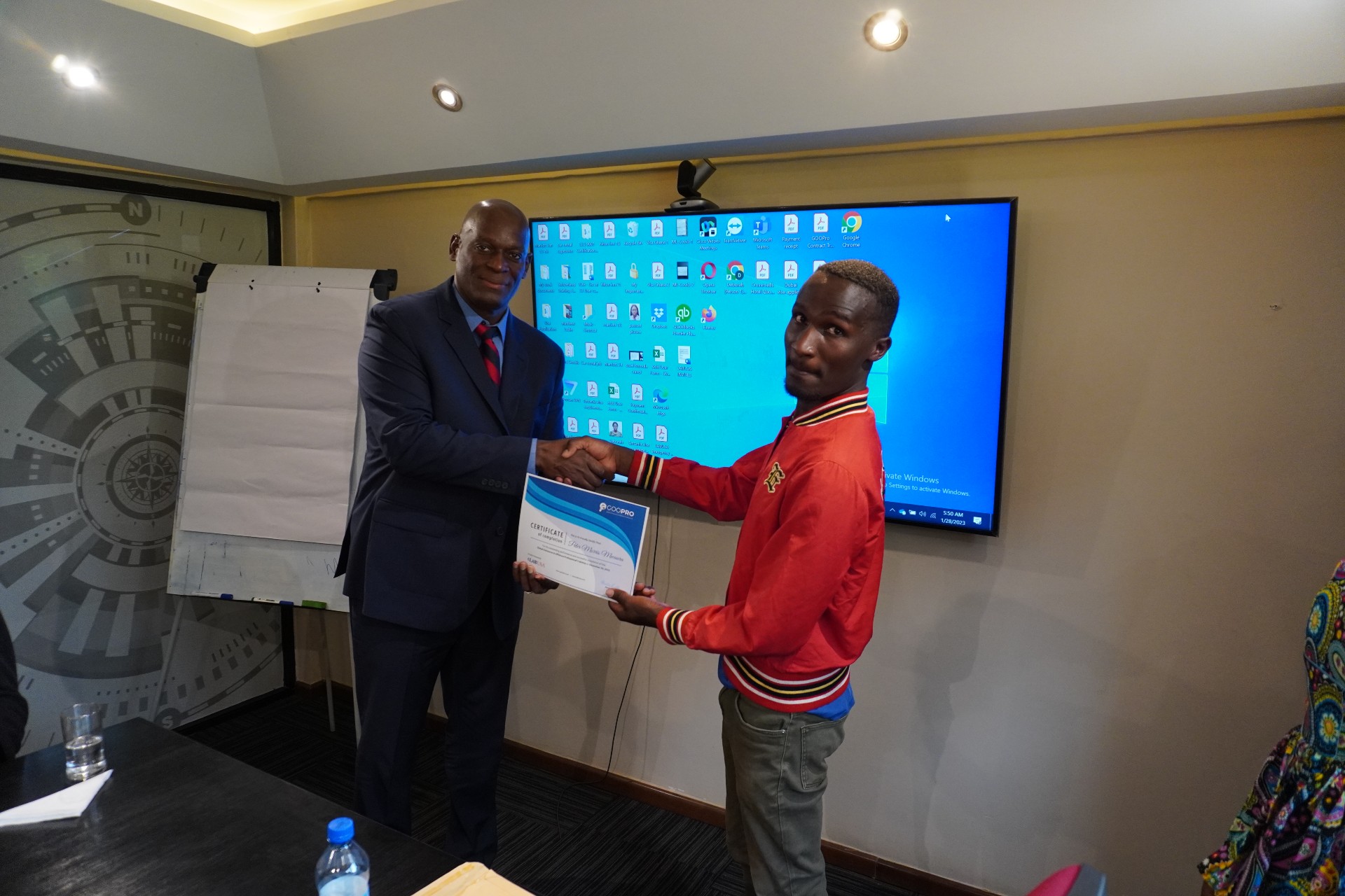 Two men shaking hands while one hands the other a certificate 