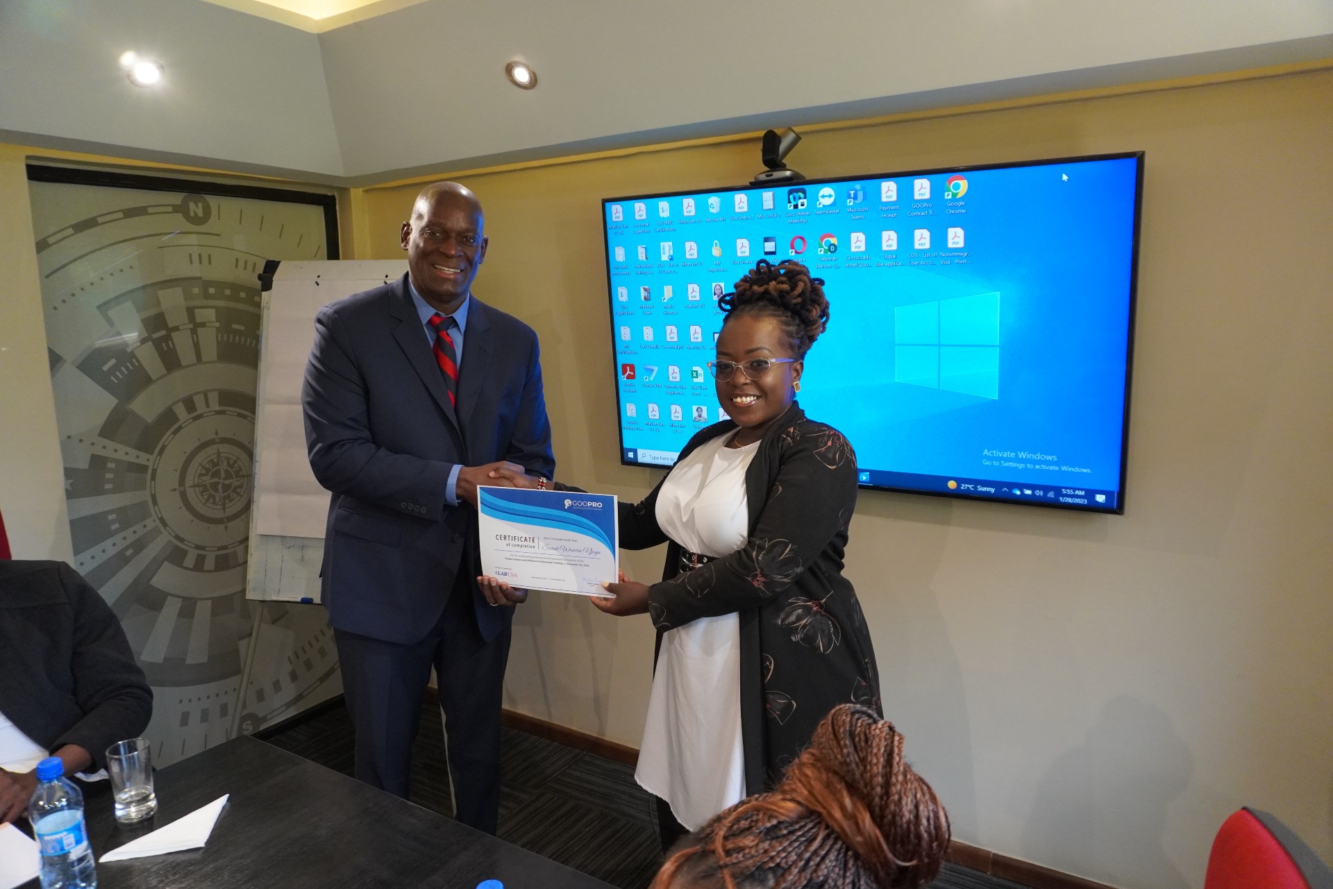 A man and a woman shaking hands while the man hands the woman a certificate 